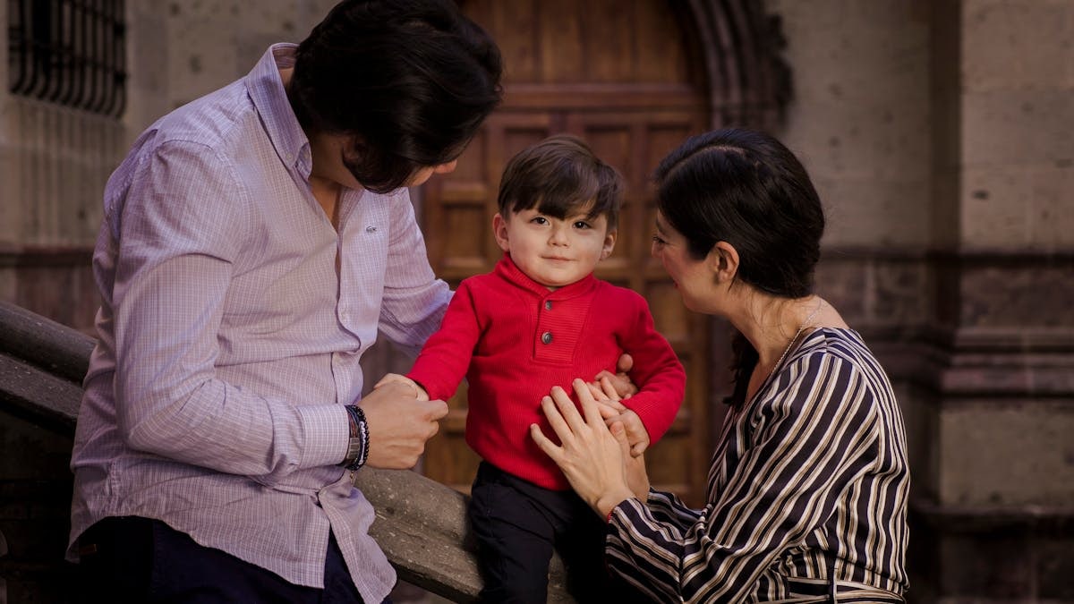 A family shares a loving moment with their young son on stone stairs.